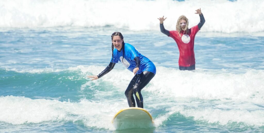 Surf coach teaching a student to ride the waves.