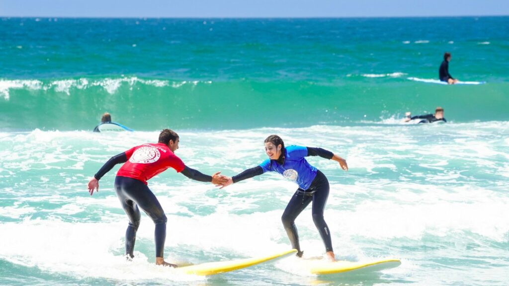 Surf instructor holding the hand of a student to help them surf safely.