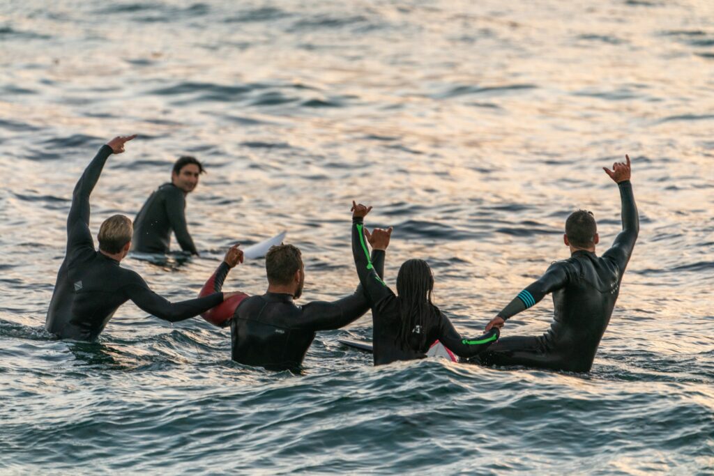 Group of surfers out on the water in a circle bonding.