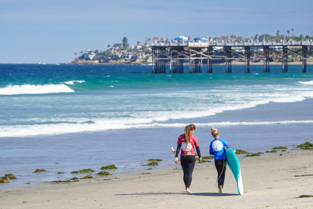 Surf instructor walking with a student along the shoreline