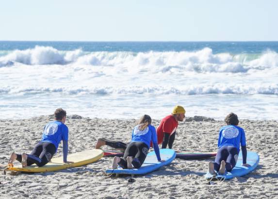 Pacific Surf School instructor teaching kids how to pop up on a surfboard