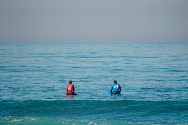 Surf instructor and student out on the water getting ready to surf on a private surf lesson.