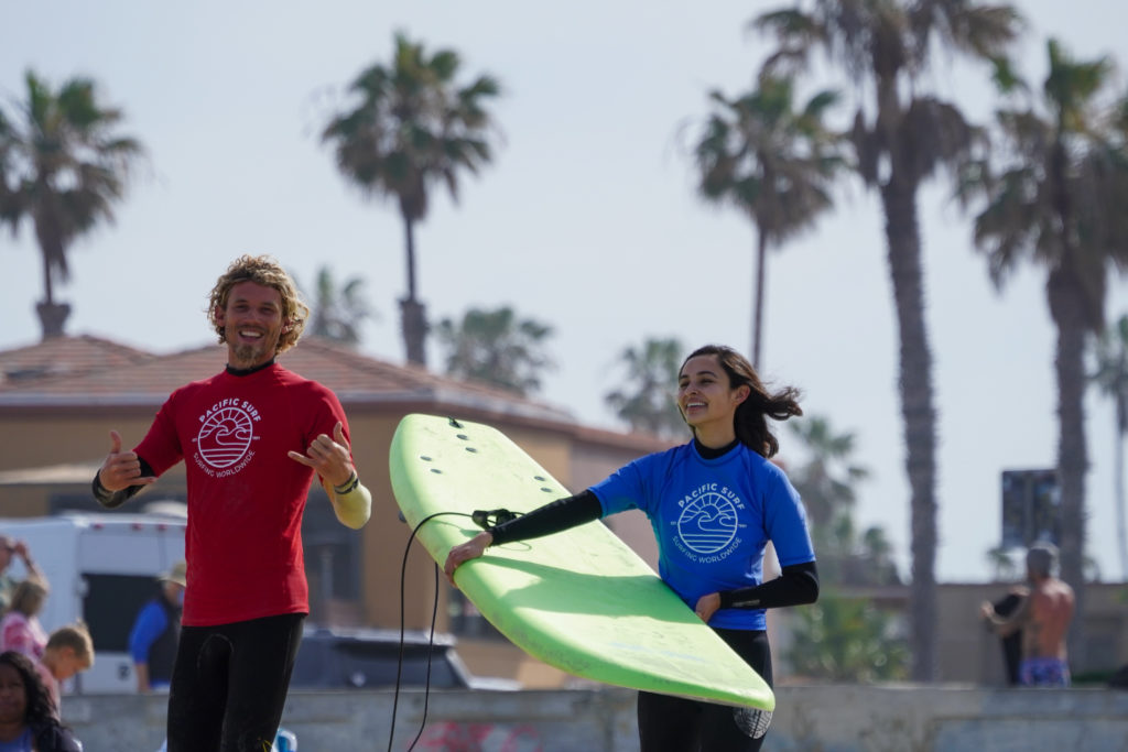 Pacific Surf School instructor and a girl holding a soft top surfboard