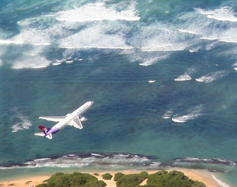 Airplane flying over surfing beach