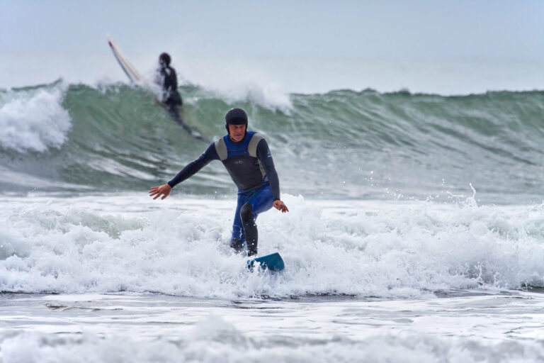 Surfer wearing helmet and wetsuit while riding wave.