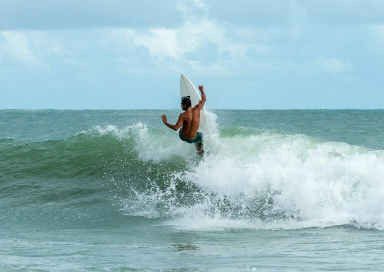 Surfer facing wave falling backwards off upended board