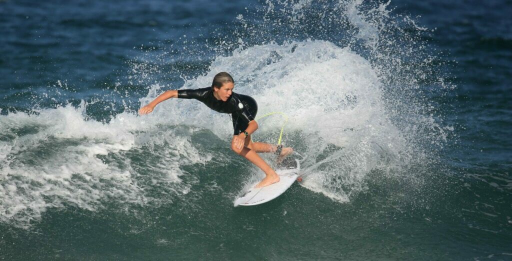 Girl riding a hard top surfboard through the waves