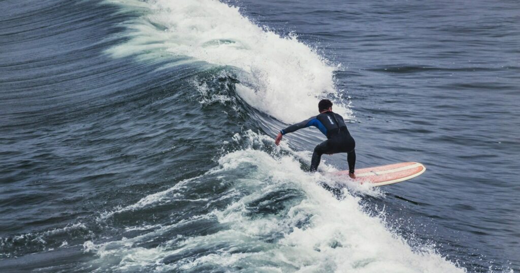 Man riding on a soft top surfboard through the waves