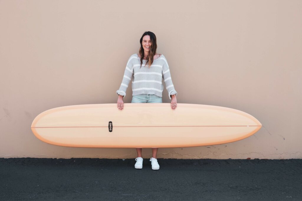 Girl holding a longboard surfboard.