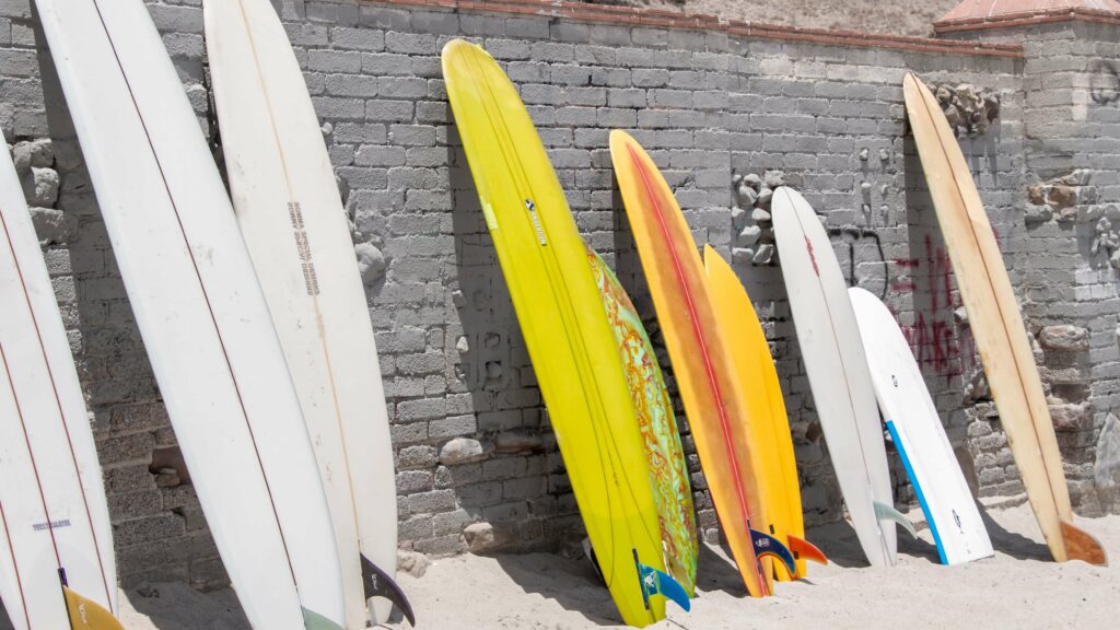 An assortment of different types of beginner surfboards against a wall.