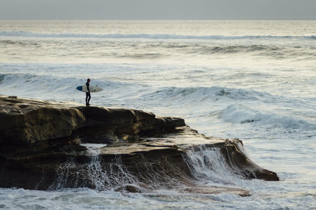 Surfer standing on a rock looking at the water conditions.