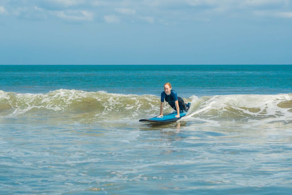 Young woman learning how to surf on small waves.