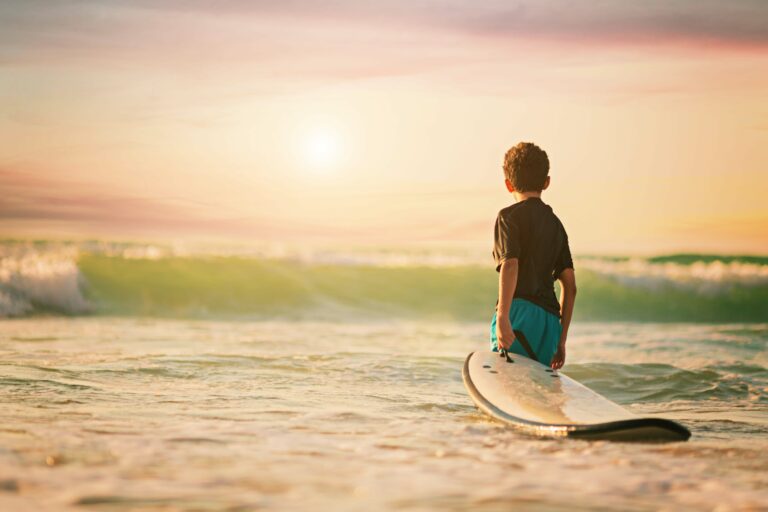 Young boy with a surfboard getting ready to learn how to surf.