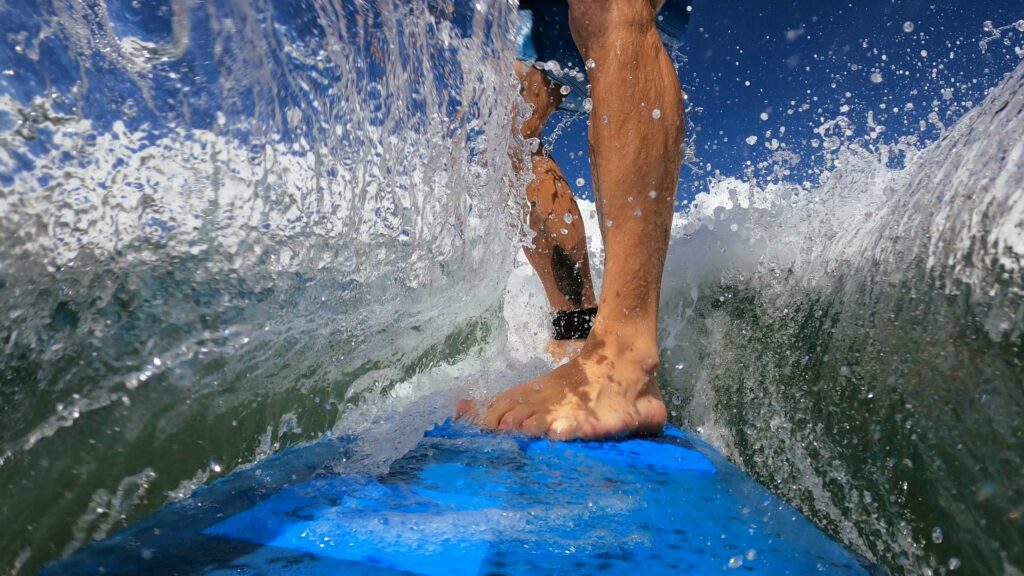 Close-up photo of a person's feet on a surfboard showing their technique.