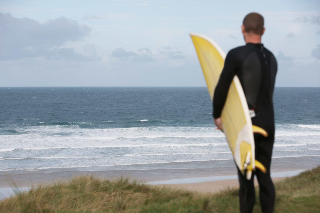 Surfer wearing a wetsuit and holding a surfboard ready to get into the water.