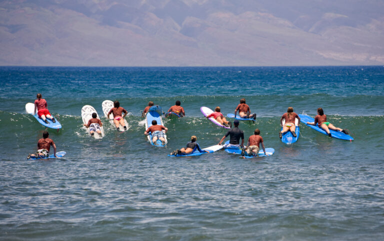 Surf school - several surfboarding students headed into an ocean swell