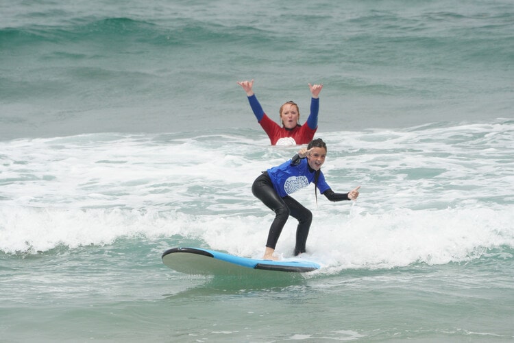 Child surfing and smiling in a surf lesson